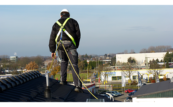 Een via zijn aanlijnpunt beveiligde medewerker aan het werk op een hellend dak.