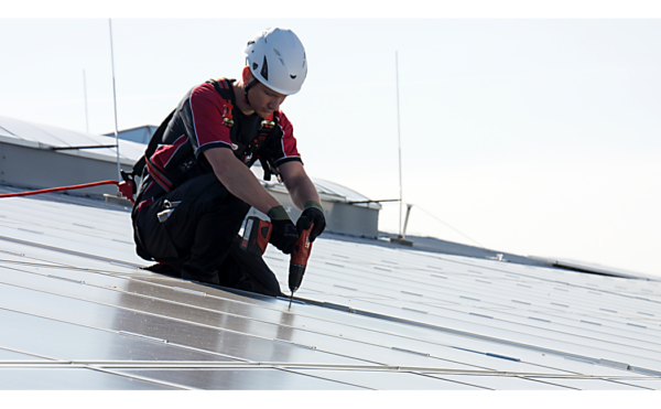 Medewerker bij het verzorging van een zonne-installatie beveiligt door ABS-Lock X-Solar ankerpunt